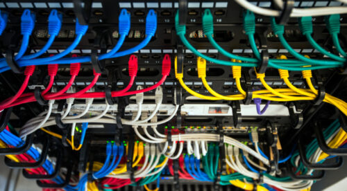 colored networking cables plugged into back of equipment